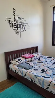 a bedroom with a bed with a happy sign on the wall at Camilyn Home Stay in General Trias