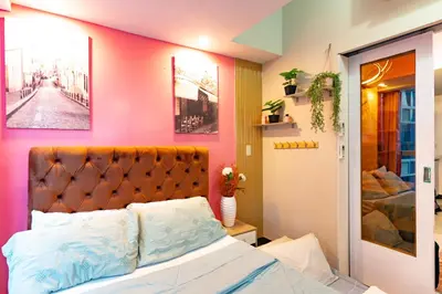a bedroom with a bed and a pink wall at Modern 1BR in Uptown BGC in Manila
