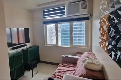 a bedroom with a bed and a window and a tv at 1 Bed Apartment Sleeps 2 with Parking in Manila