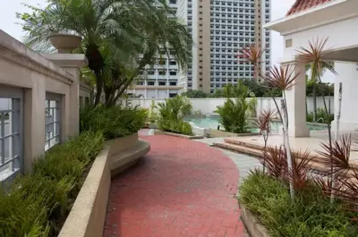 a red brick walkway next to a building with palm trees at WestParc Cedar Alabang in Manila