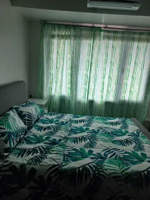 a bedroom with a bed with a green and white comforter at Air Residences Condominium Deluxe in Manila
