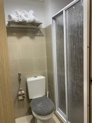 a bathroom with a toilet and a shower with towels at Katei elegantly designed 1-bedroom facing amenity in Manila