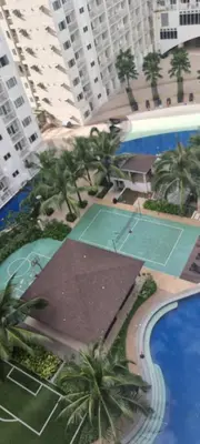 an overhead view of a tennis court with palm trees and buildings at EZStays Shore Residences in Manila