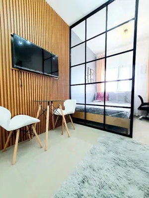 a room with two chairs and a television on a wall at Green 2 Residences Scandi-Industrial Hotel Type Interior in Dasmariñas