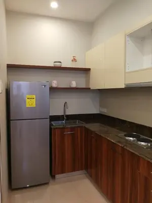 a kitchen with a stainless steel refrigerator and wooden cabinets at Adria Residences - Ruby Garden - 2 Bedroom for 4 person in Manila