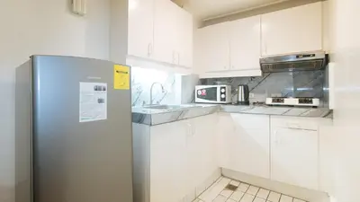 a kitchen with white cabinets and a refrigerator at Sunette Tower Makati in Manila
