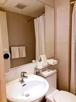 a bathroom with a sink and a toilet and a mirror at Azure SKYVIEW PENTHOUSE minimalist unit in Manila