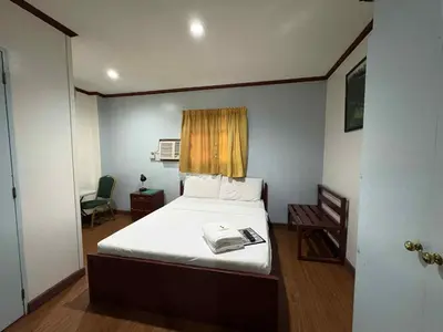 a small bedroom with a bed and a chair at DUCK INN AND RESTAURANT in Manila