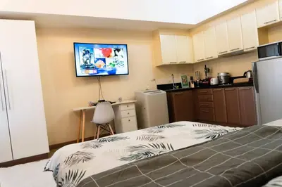a kitchen with a bed and a tv on the wall at A2J Luxury Venice Studio Suite Near BGC Malls in Manila