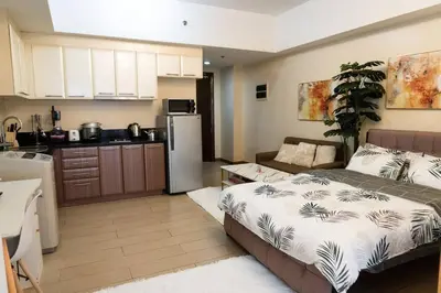 a kitchen and a bedroom with a bed and a refrigerator at A2J Luxury Venice Studio Suite Near BGC Malls in Manila