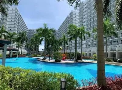 a large swimming pool with palm trees and buildings at Shell Residences C15 Shortwalk Sm Mall Of Asia/Airport in Manila