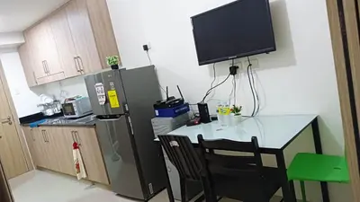 a kitchen with a table and a television on the wall at Shore Residence D10 Near Mall Of Asia- Airport in Manila