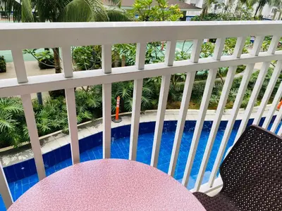 a pink table and chairs on a balcony with a pool at Shore Residence D12 Near Airport- SM Mall Of Asia in Manila
