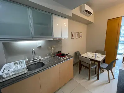 a kitchen with a sink and a table with chairs at One Uptown Residence BGC in Manila