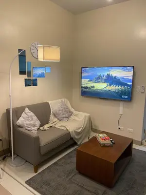 a living room with a couch and a flat screen tv at One Uptown Residence BGC in Manila