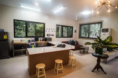 a kitchen and living room with a counter and stools at Tagaytay Foothills Cherimoya Farm Staycation in Biboyan