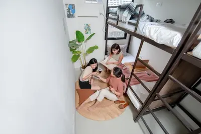 three girls sitting on the floor in a room with bunk beds at The Grid Co-Living Managed by HII in Manila