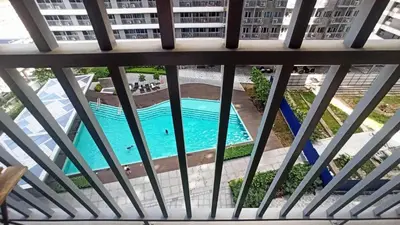 a view of a pool from the balcony of a building at Cozy 1Br with Netflix & Balcony Pool View Condo in Manila
