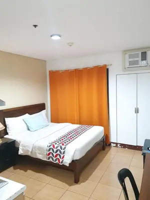 a bedroom with a bed with an orange curtain at Sab R. Bel air soho in Manila