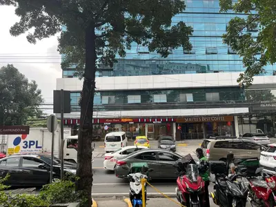 a parking lot with cars and motorcycles in front of a building at The Cozy Place Condo in Pasig Phil in Manila