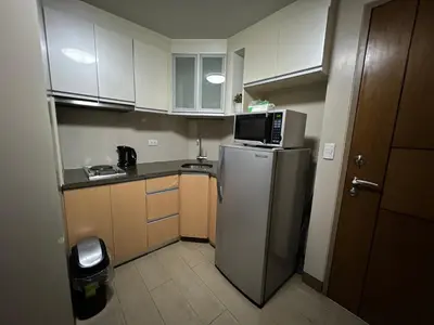 a small kitchen with a refrigerator and a microwave at Cozy condo near Airport Manila in Manila