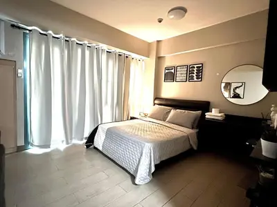 a bedroom with a bed and a large window at Cozy condo near Airport Manila in Manila