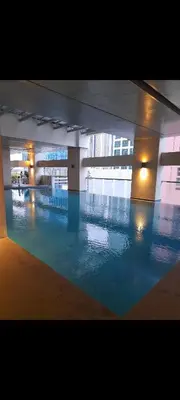 a large swimming pool with blue water in a building at VICTORIA DE MAKATI Two (2) Bedroom Up and Down Condo in Manila