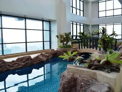 a swimming pool in a building with a rock wall at Relaxing Big Studio Bedroom in Manila