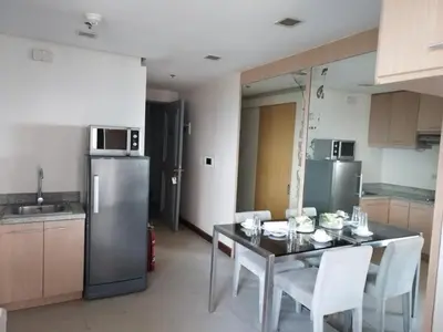 a kitchen with a table with chairs and a refrigerator at Relaxing Big Studio Bedroom in Manila
