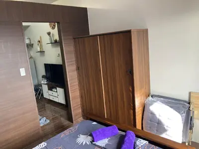 a bedroom with a wooden cabinet and a bed with purple pillows at Makati amazing view Penthouse studio, Air Residence, fast internet in Manila