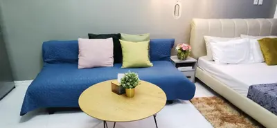 a living room with a blue bed and a table at Elite Pod at Knightsbridge Residences Makati in Manila