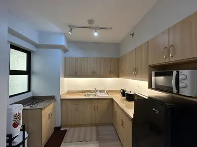 a kitchen with wooden cabinets and a sink and a microwave at Alea Residences in Manila