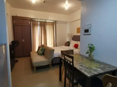 a living room with a bed and a dining room table at Staycation @150 Newport pasay city in Manila