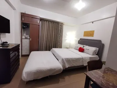 a bedroom with two beds and a table and a television at Staycation @150 Newport pasay city in Manila
