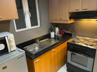 a small kitchen with a sink and a stove at Poolview Family Room Greenbelt Makati in Manila