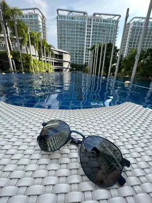 a pair of sunglasses sitting on a table next to a pool at The Carribean Suites by Azure in Manila