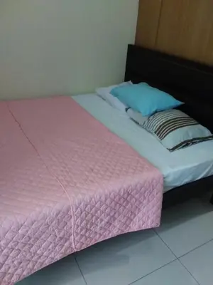 a bed with a pink blanket and a blue pillow at Condo at Shell Residences in Manila