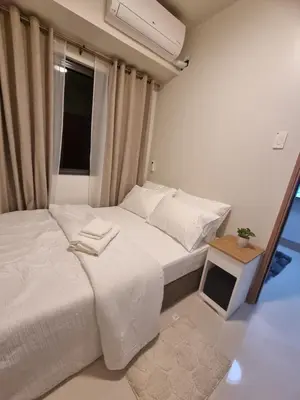 a bedroom with a bed with white sheets and a window at Shore 3 Residences Mall of Asia Pool view Netflix free wifi in Manila