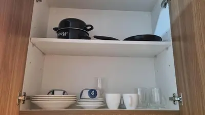 a cupboard filled with bowls and plates and utensils at Shore 3 Residences Mall of Asia Pool view Netflix free wifi in Manila