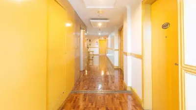an empty hallway with yellow walls and wooden floors at Aloha Hotel Roxas Boulevard Manila in Manila