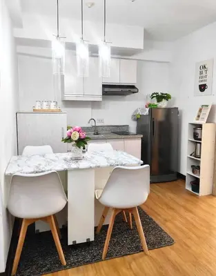 a kitchen with a table with white chairs and a refrigerator at Lancris Residences 2 Bedroom Entire Apartment near Airport with Pool in Manila