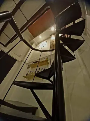 a spiral staircase with a clock in a building at Adorable Lounge - 1 Bedroom loft w/home cinema in Manila