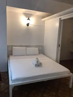 a white bed with a teddy bear sitting on it at Alta Vitas Daily in Manila