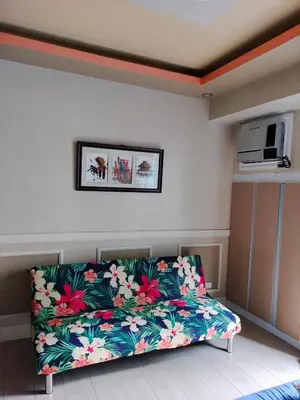 a living room with a couch with flowers on it at Staycation Near Airport and resorts World Manila in Manila