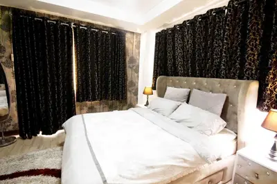 a bedroom with a white bed with black curtains at McKinley Hill, BGC 3 Bedroom Unit Venice Mall Walking Distance in Manila