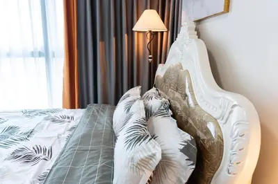 a bed with pillows on it next to a lamp at A2J Luxury 2BR BGC Uptown Suite Near Uptown Mall in Manila