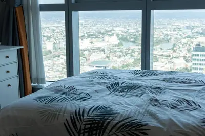 a bed in a room with a large window at A2J Luxury 2BR BGC Uptown Suite Near Uptown Mall in Manila