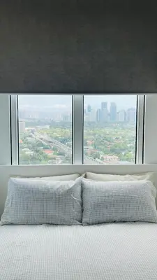 a bed with a large window with a view of a city at San Lorenzo Place in Manila