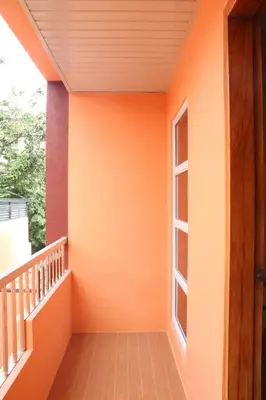 a balcony with an orange wall and a window at Anicia Guesthouse Rooms in Manila