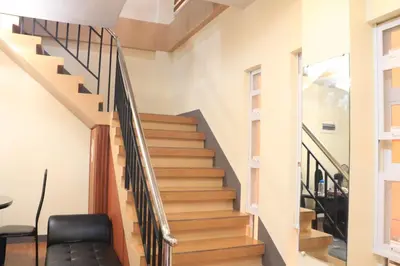 a staircase in a house with a black leather chair at Anicia Guesthouse Units in Manila